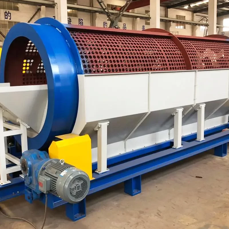 a large, industrial trommel screen, a vital piece of equipment commonly used in recycling facilities to separate materials by size. This cylindrical screen rotates to sort materials, with smaller particles falling through the holes while larger items continue to the end of the trommel.