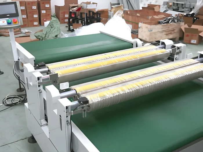 The image shows an automatic counting machine used in a PVC/nitrile glove production line. The machine features a conveyor belt system with rollers and a control panel for automated operations. The background includes boxes and other materials, indicating an industrial setting for glove manufacturing and packaging.