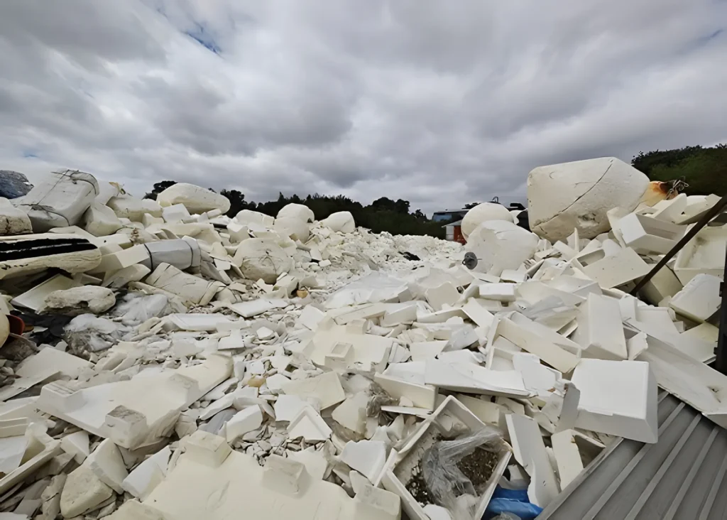 Large pile of white foam debris under cloudy sky.